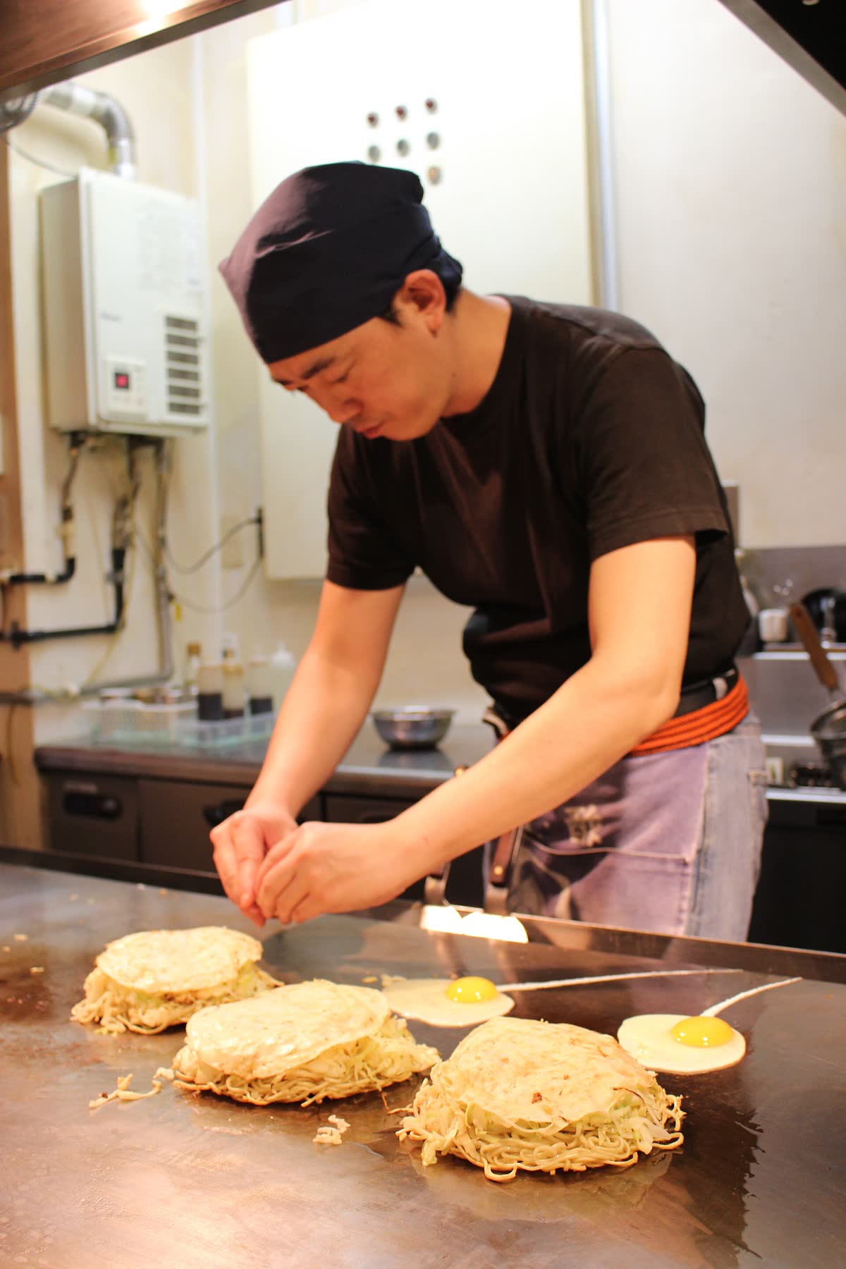 Hiroshima-style okonomiyaki being cooked on a hotplate